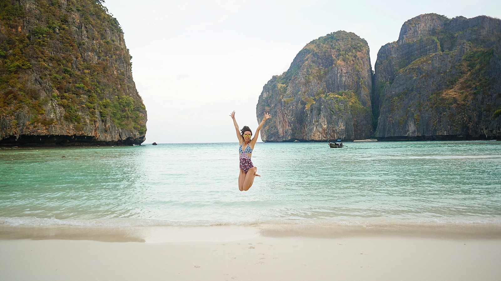 diana elizabeth blogger in Koh phi phi island Maya bay jumping in sand with hands up in the air