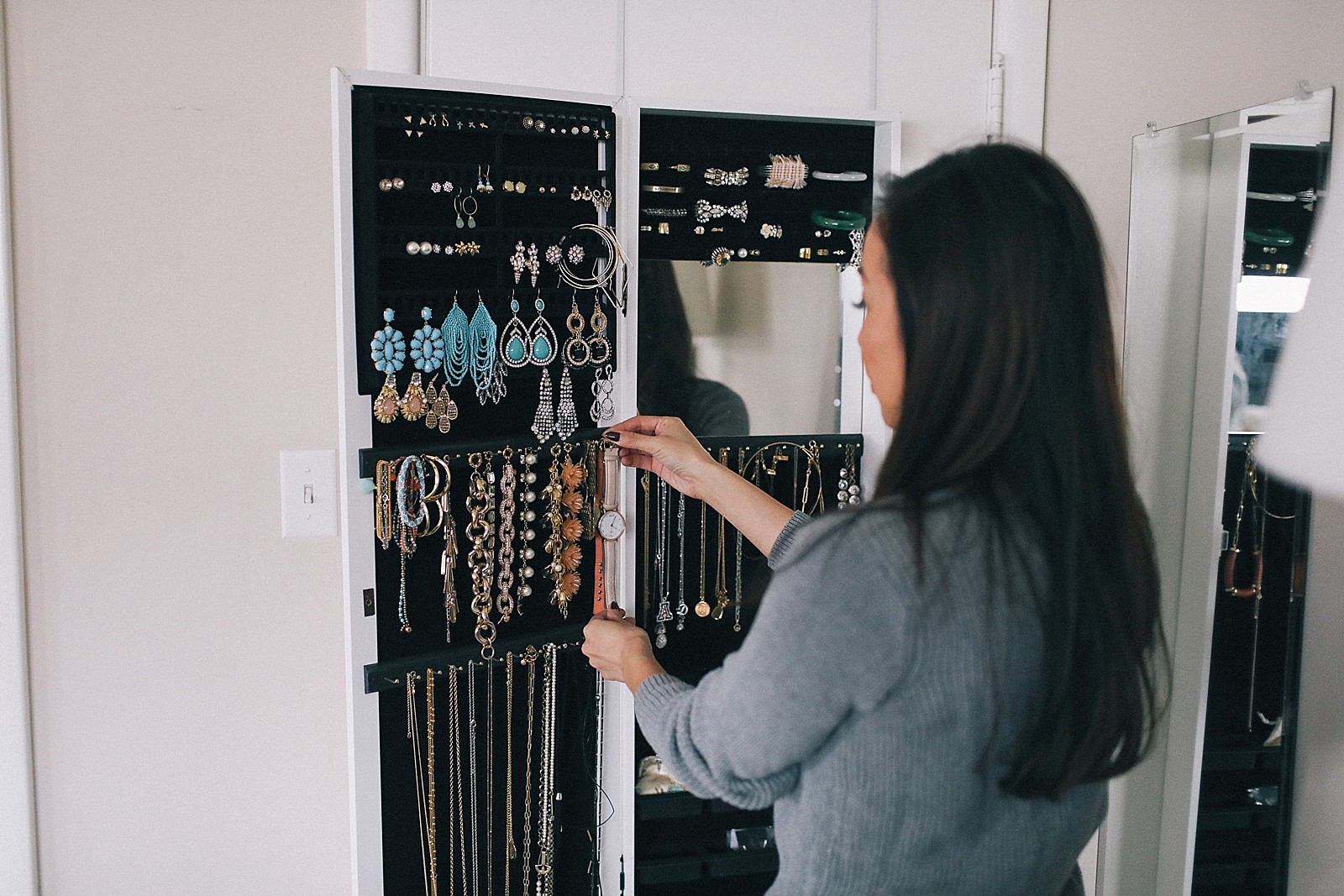 behind the door jewelry cabinet organization holds many bracelets earrings and necklaces 