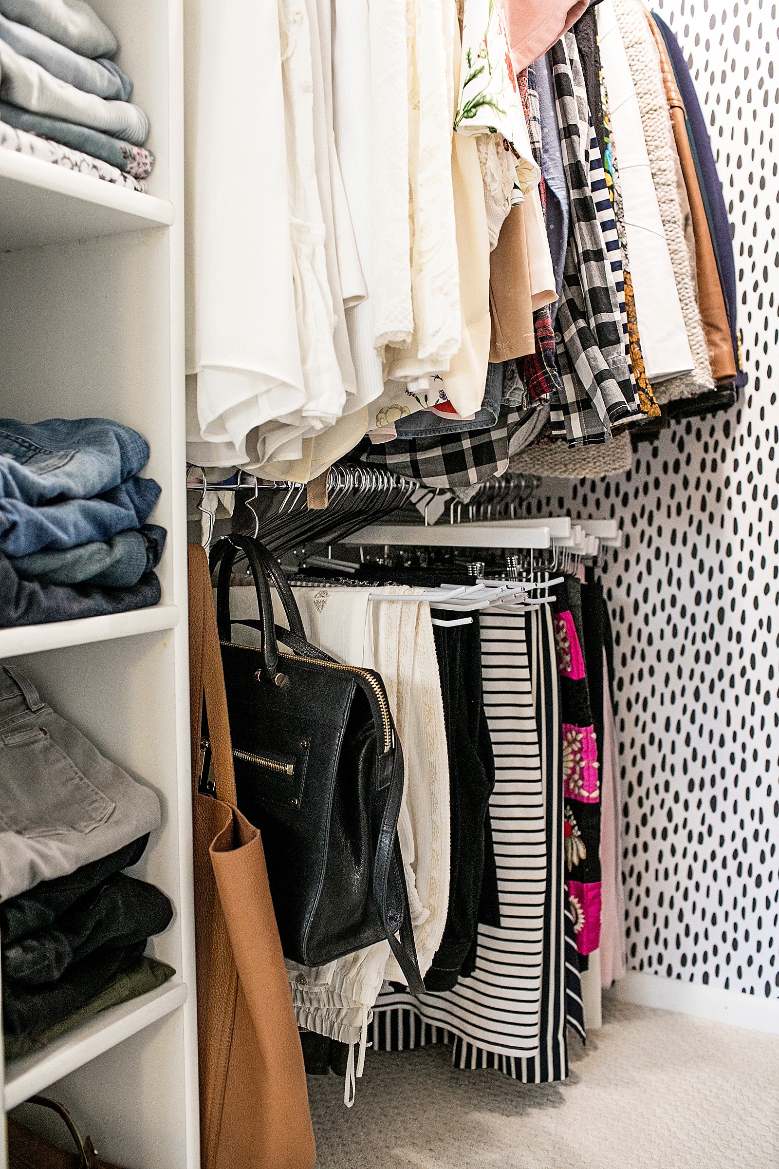 white wood pant hangers on chrome oval rods and purse hooks to keep a tiny closet organized