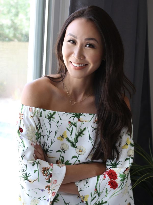 Lifestyle blogger Diana Elizabeth against window in floral strapless top