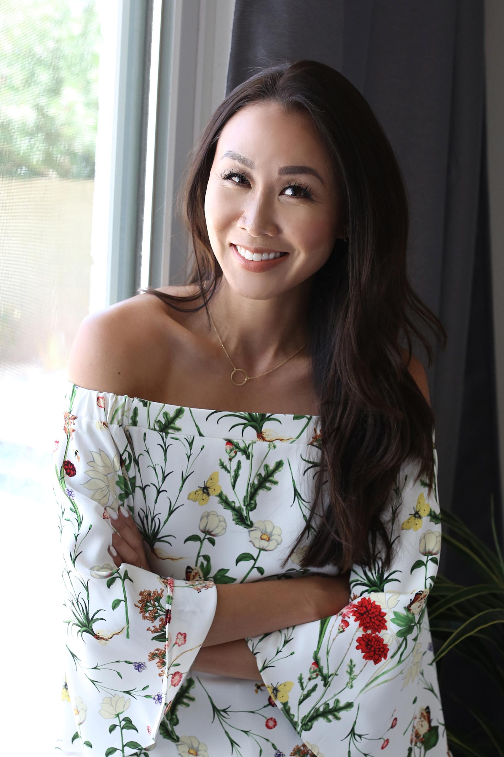 Lifestyle blogger Diana Elizabeth against window in floral strapless top