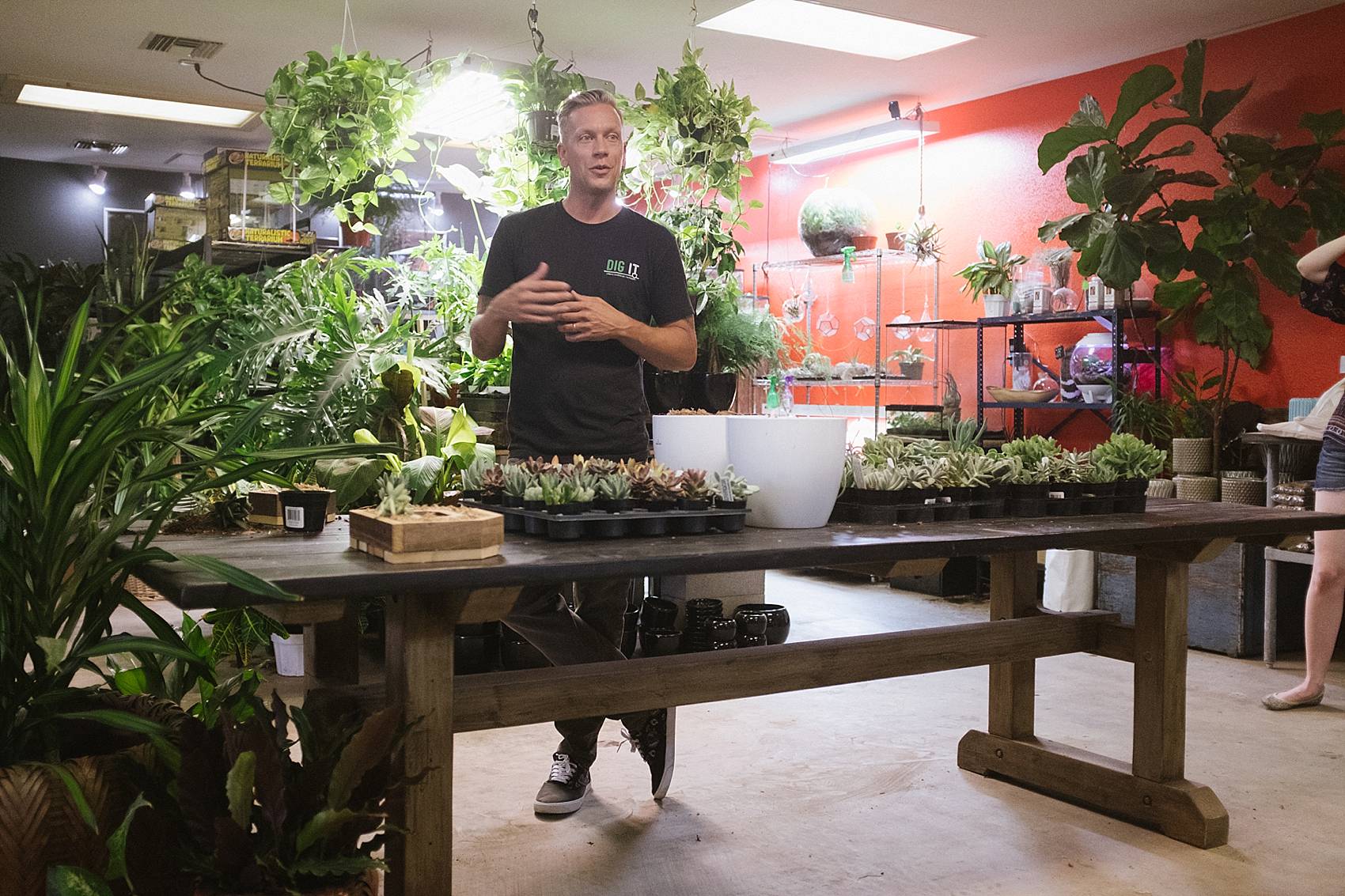 owner of grow it in phoenix a nursery explaining how to take care of succulents standing behind a table giving presentation 