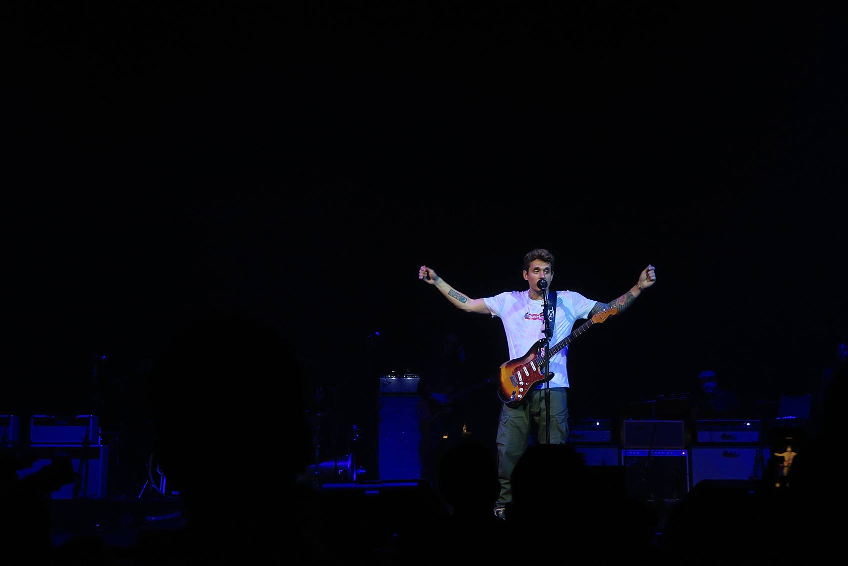 John Mayer performing in Phoenix on stage for his The Search for Everything Tour black background his hands are up talking about the universe and his hit songs