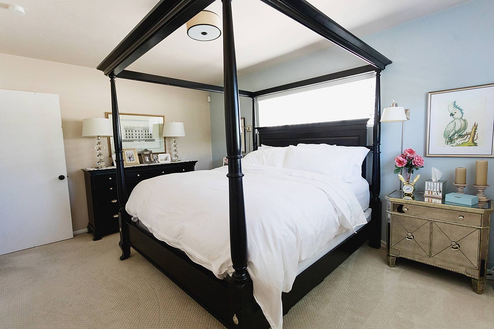 traditional bedroom with mirror nightstands black canopy bed with all white bedding white carpet