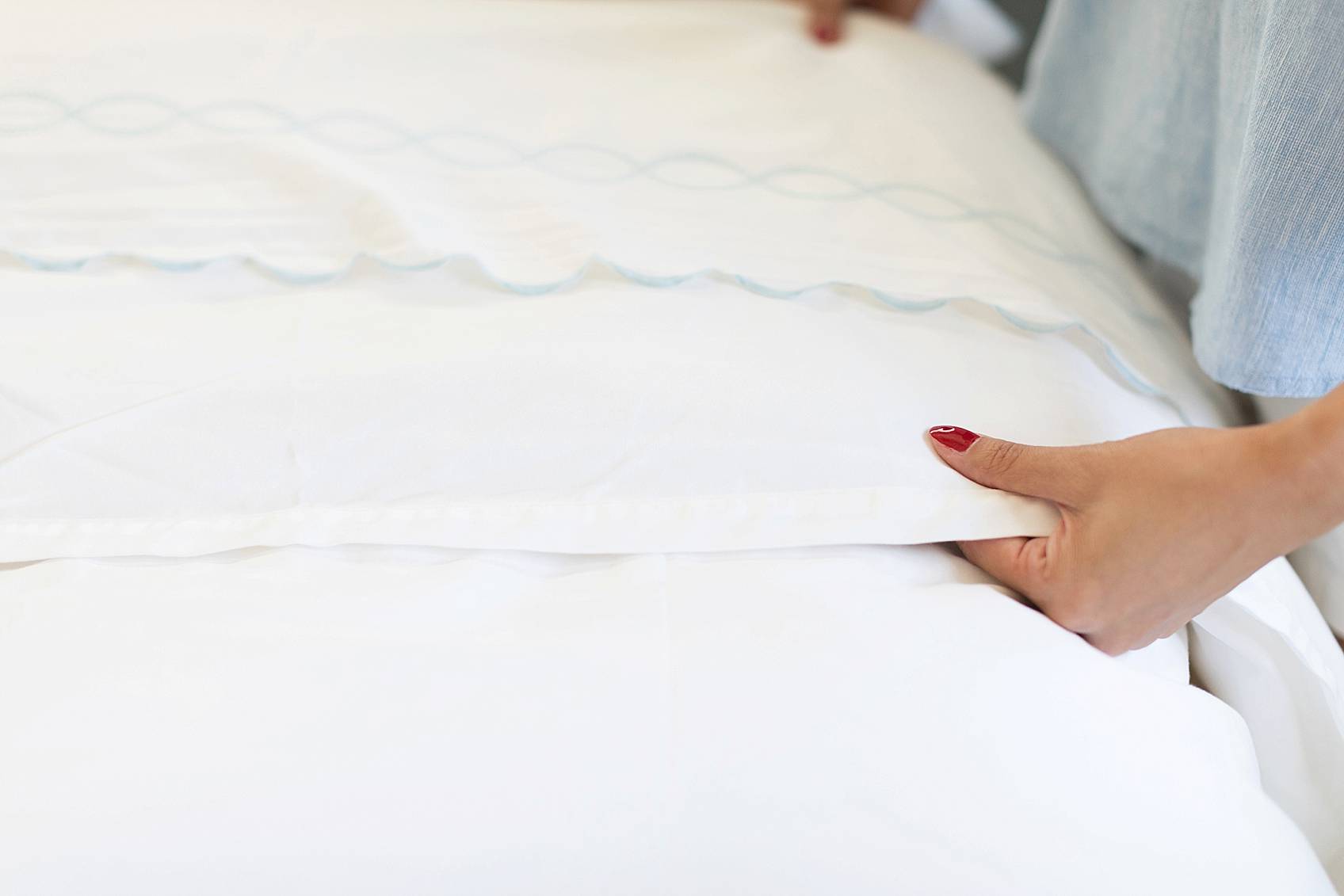 lifestyle blogger diana Elizabeth fixing all white bedding, red nails, scalloped blue sheets, Serena and lily bedding