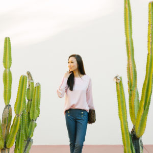 diana Elizabeth lifestyle blogger standing in front of white wall with cactus on both sides of her taken at heard museum in phoenix arizona