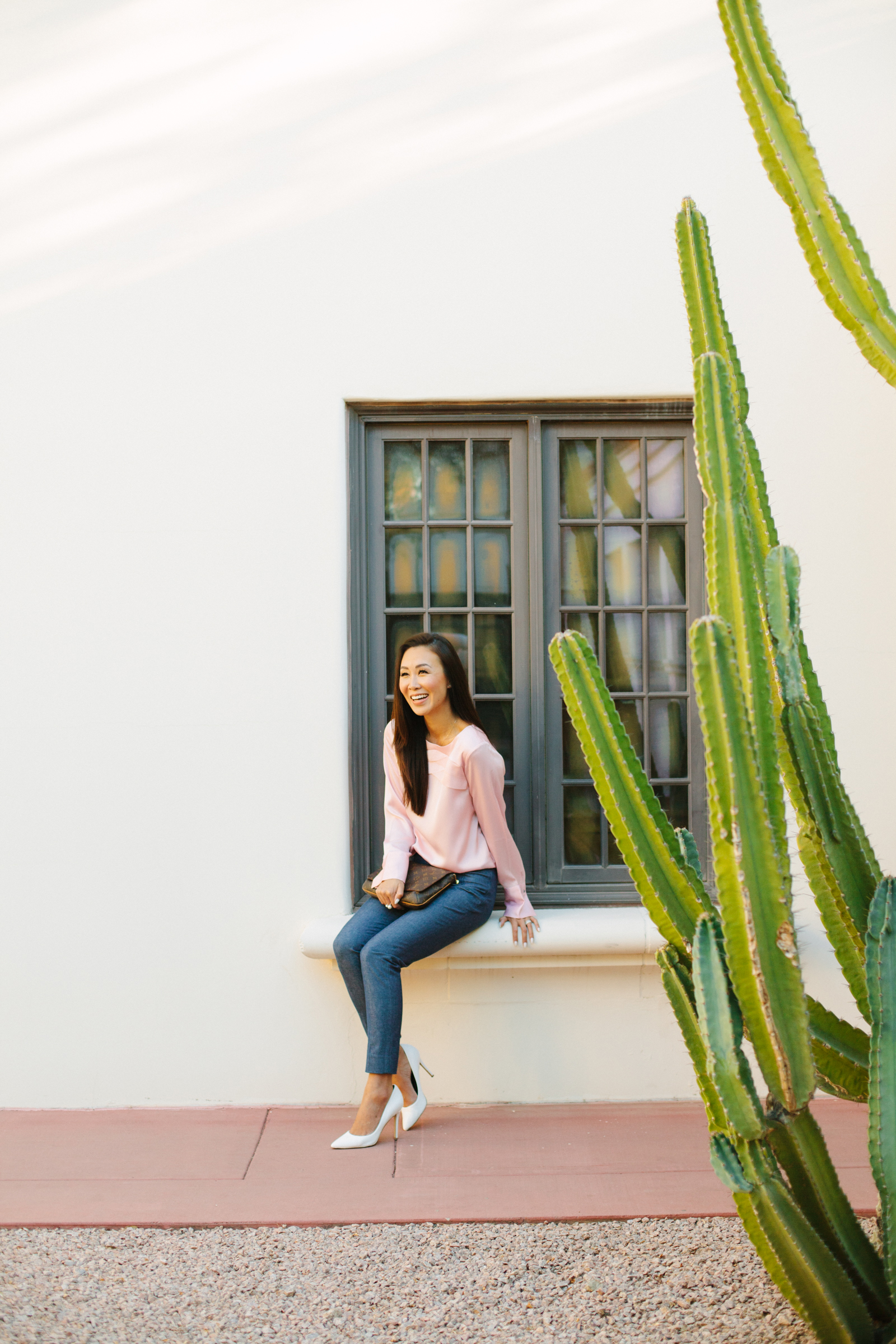 diana Elizabeth lifestyle blogger sitting on window sill in front of white wall with cactus on both sides of her taken at heard museum in phoenix arizona