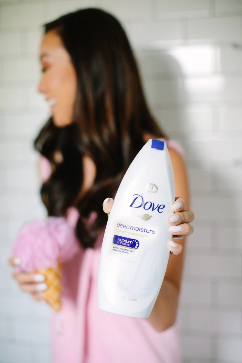 holding dove beauty wash in shower with ice cream body pouf