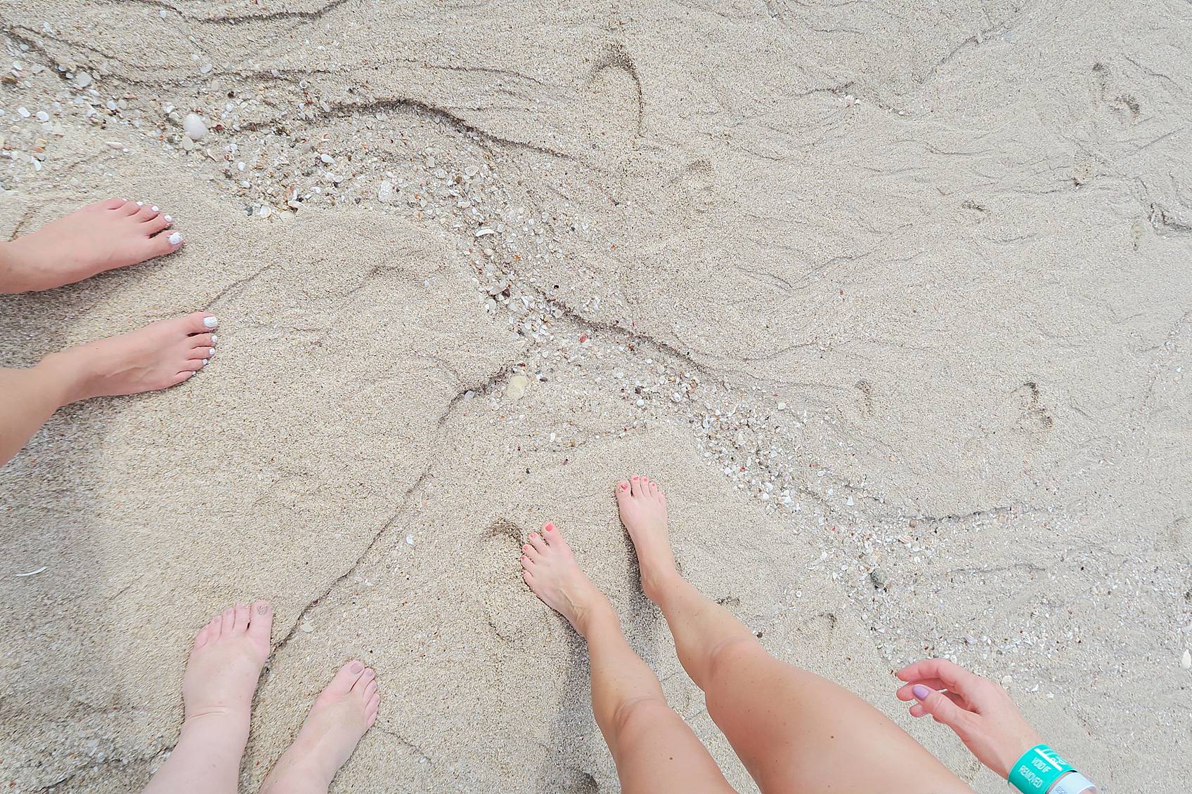 feet in sand with seashells