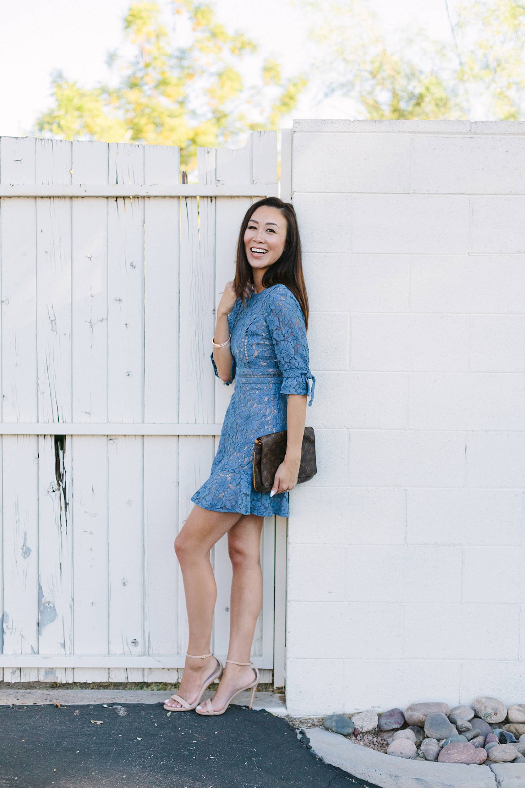 blue lace dress on lifestyle blogger diana elizabeth against white fence