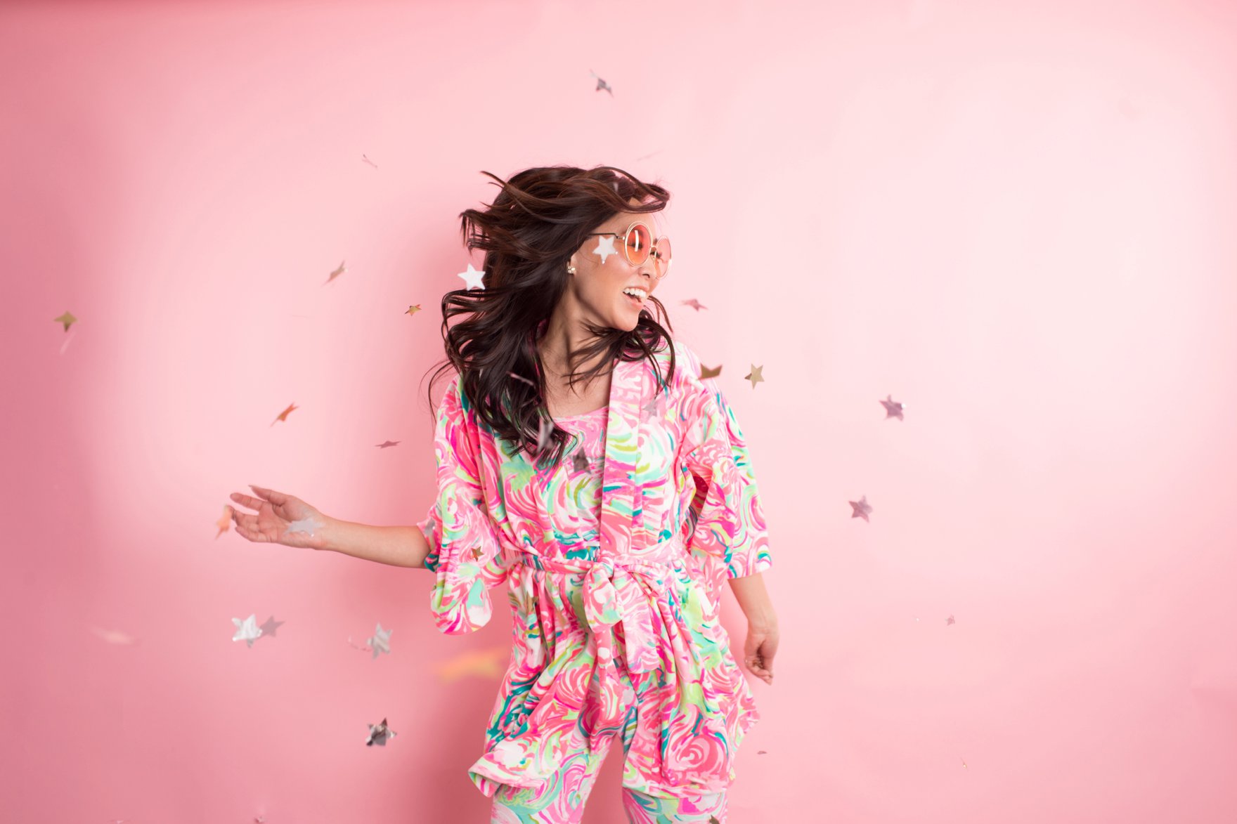 Lilly Pulitzer Christmas pajama party Diana Elizabeth in front of pink background and star confetti