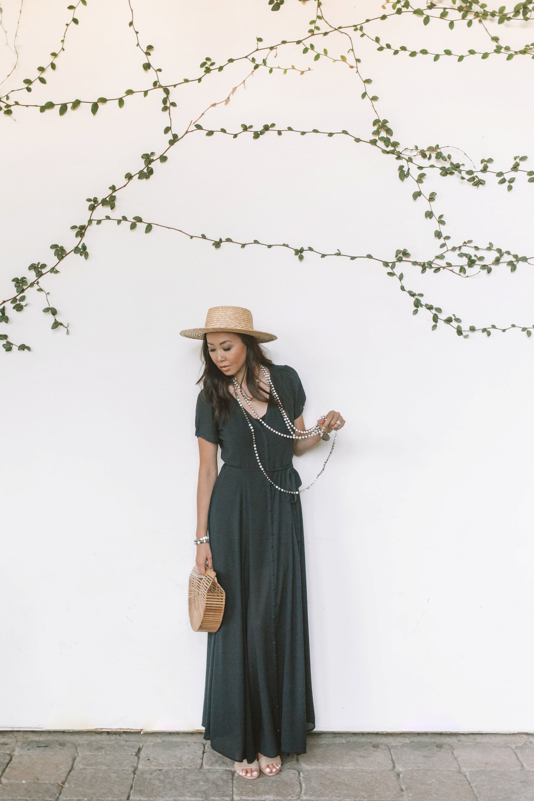 black maxi dress long pearl crochet necklace with hat, sunny day in scottsdale blogger Diana Elizabeth in front of white vines