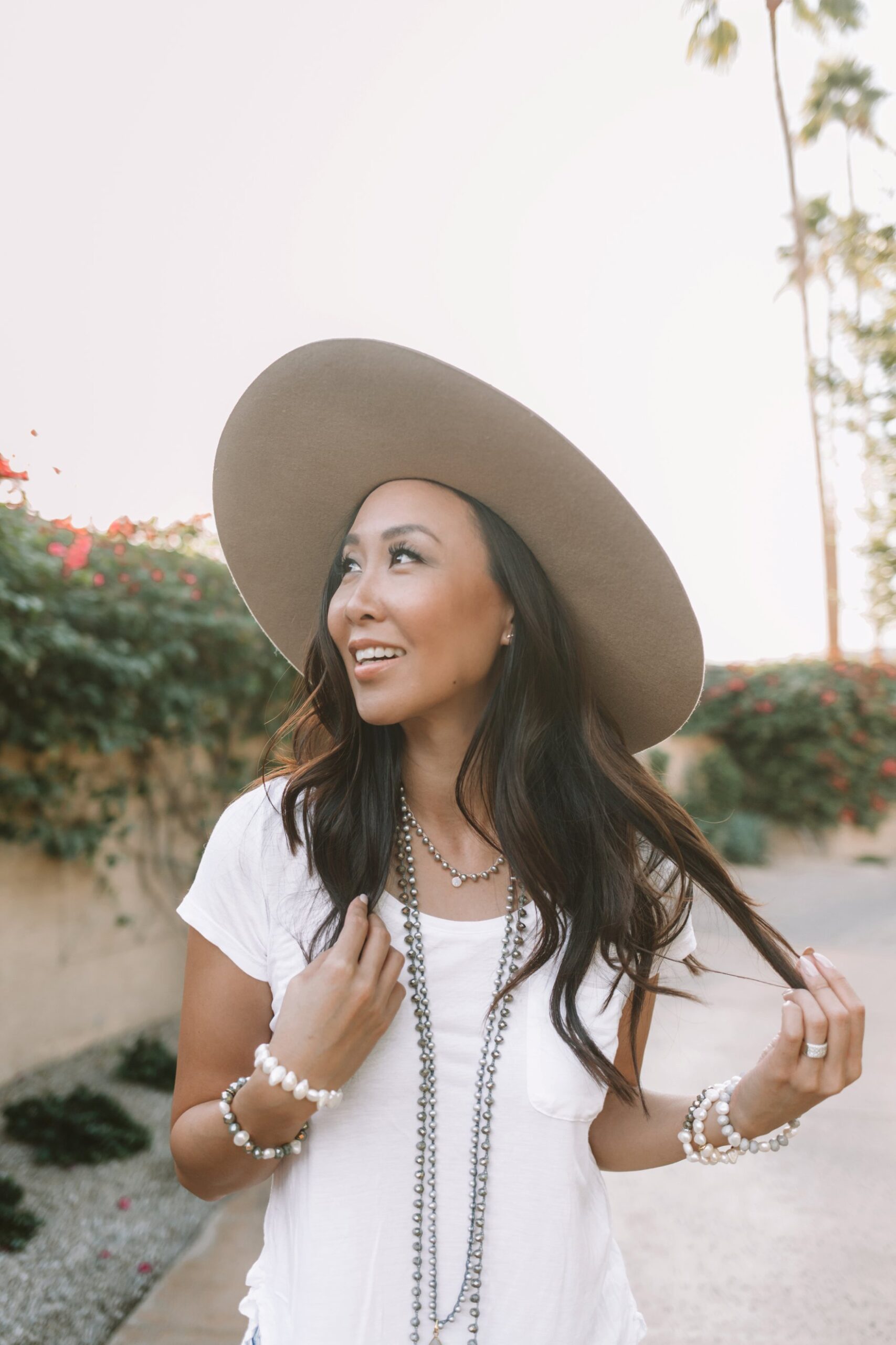 big felt hat with basic tee shirt and pearl necklaces. lifestyle style blogger Diana Elizabeth pulling strands of hair
