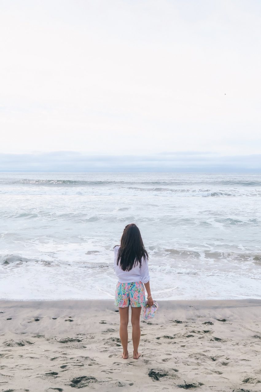 Carlsbad state beach wearing Lilly Pulitzer ocean view boardshort Diana Elizabeth blogger walking on beach wearing linen button up shirt