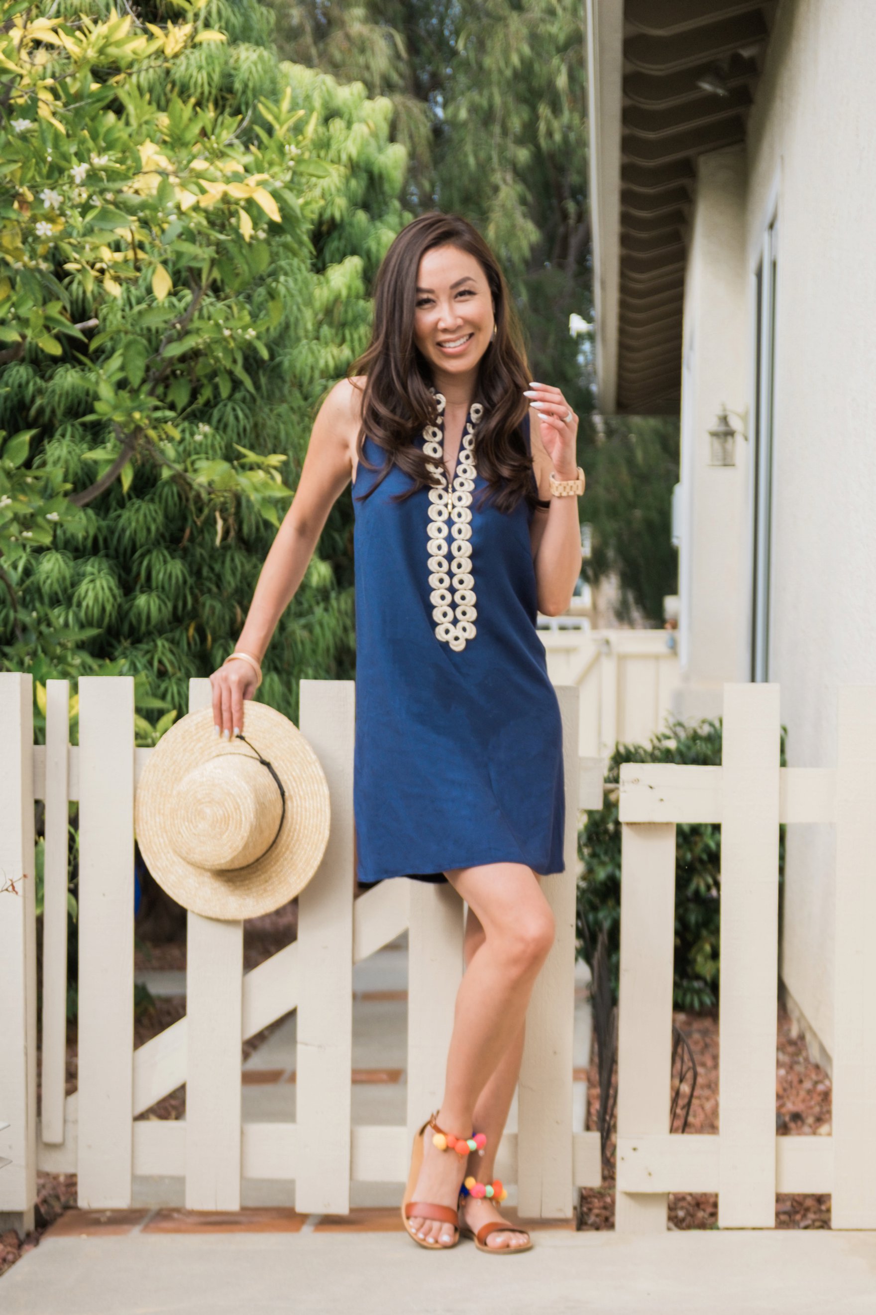 navy Lilly pulitzer Jane shift dress with sunhat on blogger Diana Elizabeth in San Diego leaning against white picket fence