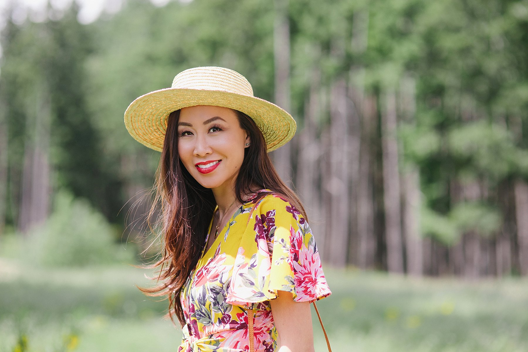 yellow floral jumpsuit by Tahari ASL on blogger Diana Elizabeth wearing straw boater hat and wicker tote standing in Bear Mountain in Victoria BC Canada