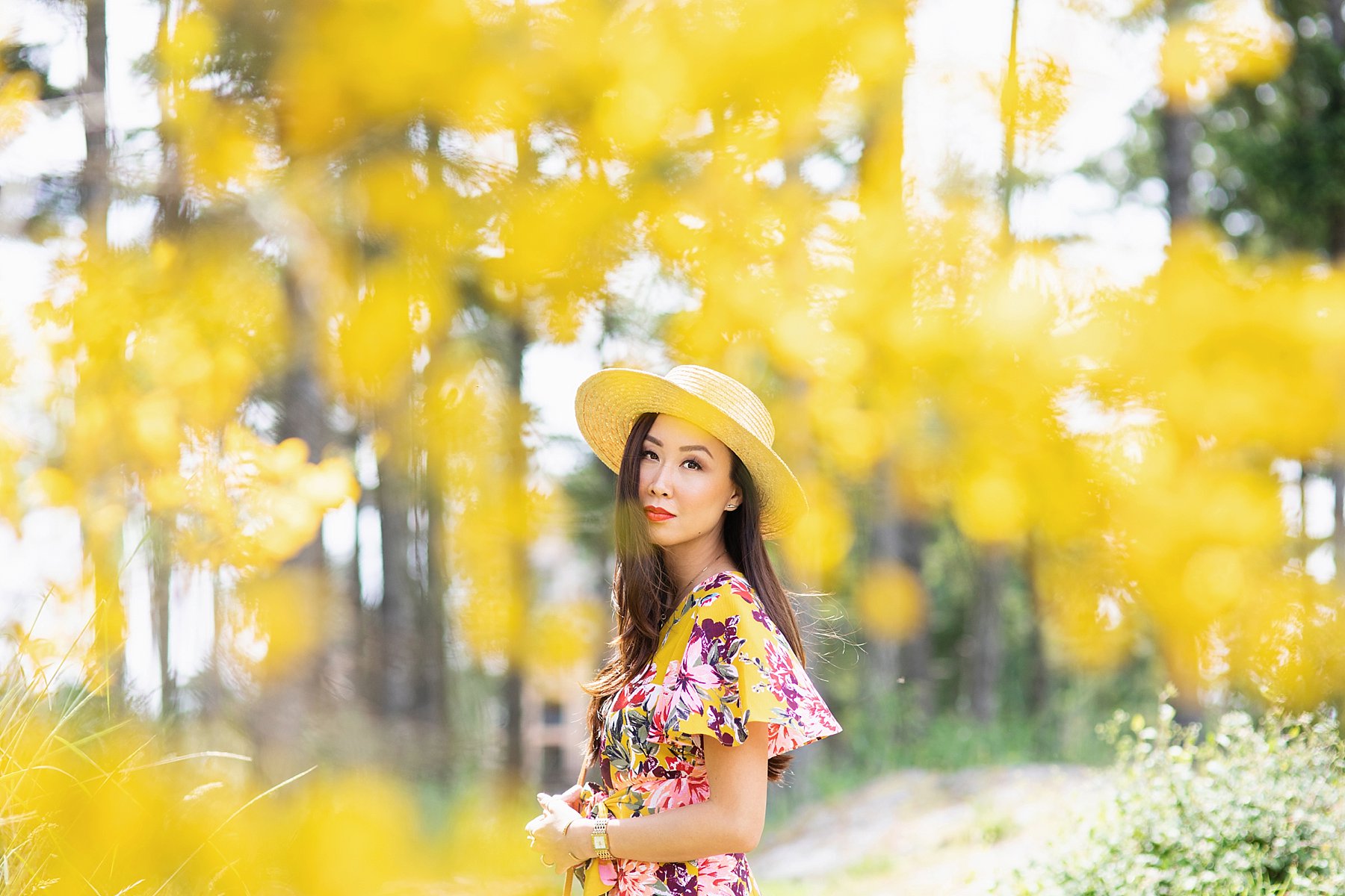 yellow floral jumpsuit by Tahari ASL on blogger Diana Elizabeth wearing straw boater hat and wicker tote standing in Bear Mountain in Victoria BC Canada