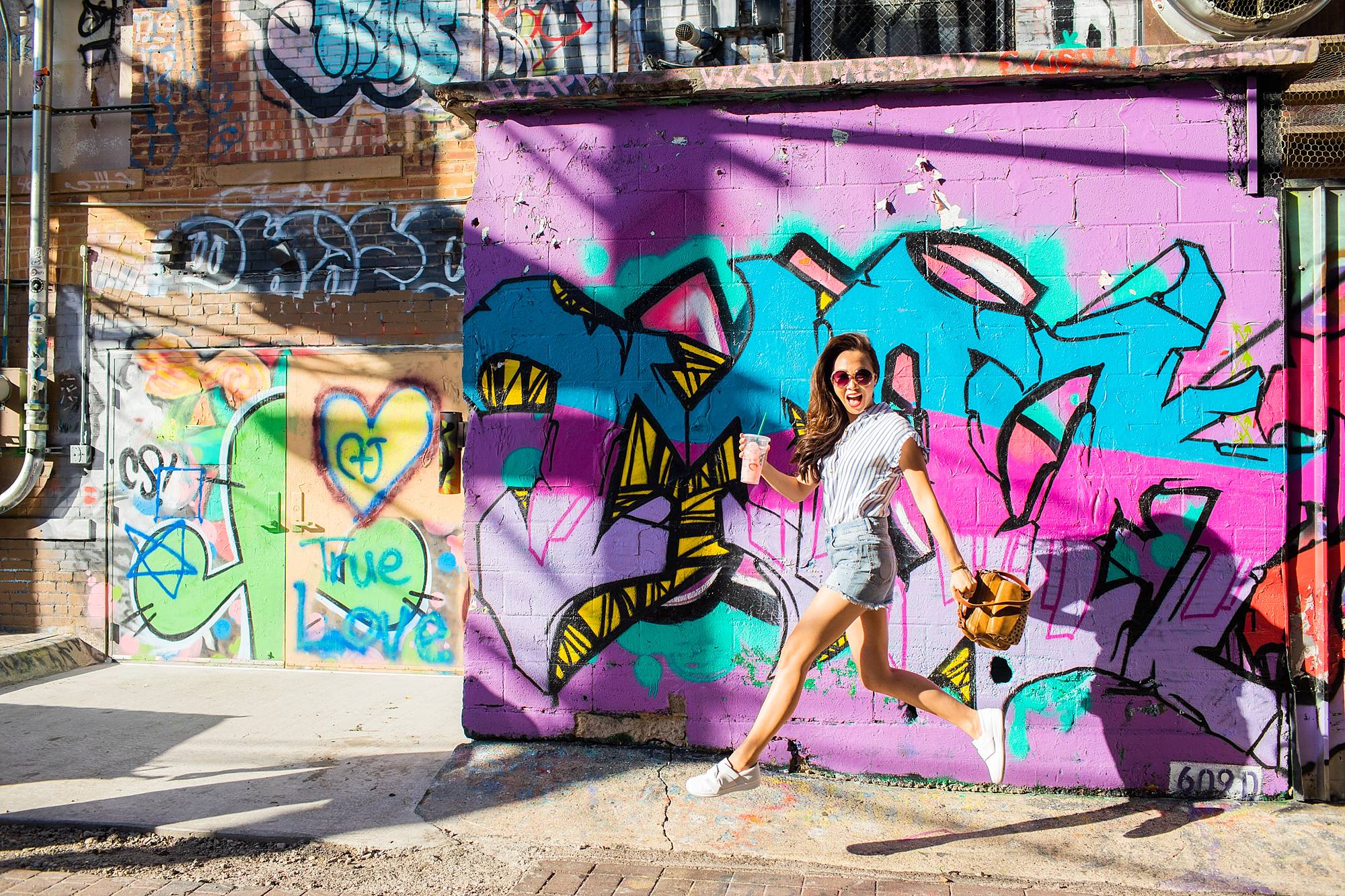 art alley graffiti walls in rapid city, South Dakota blogger Diana Elizabeth jumping in air