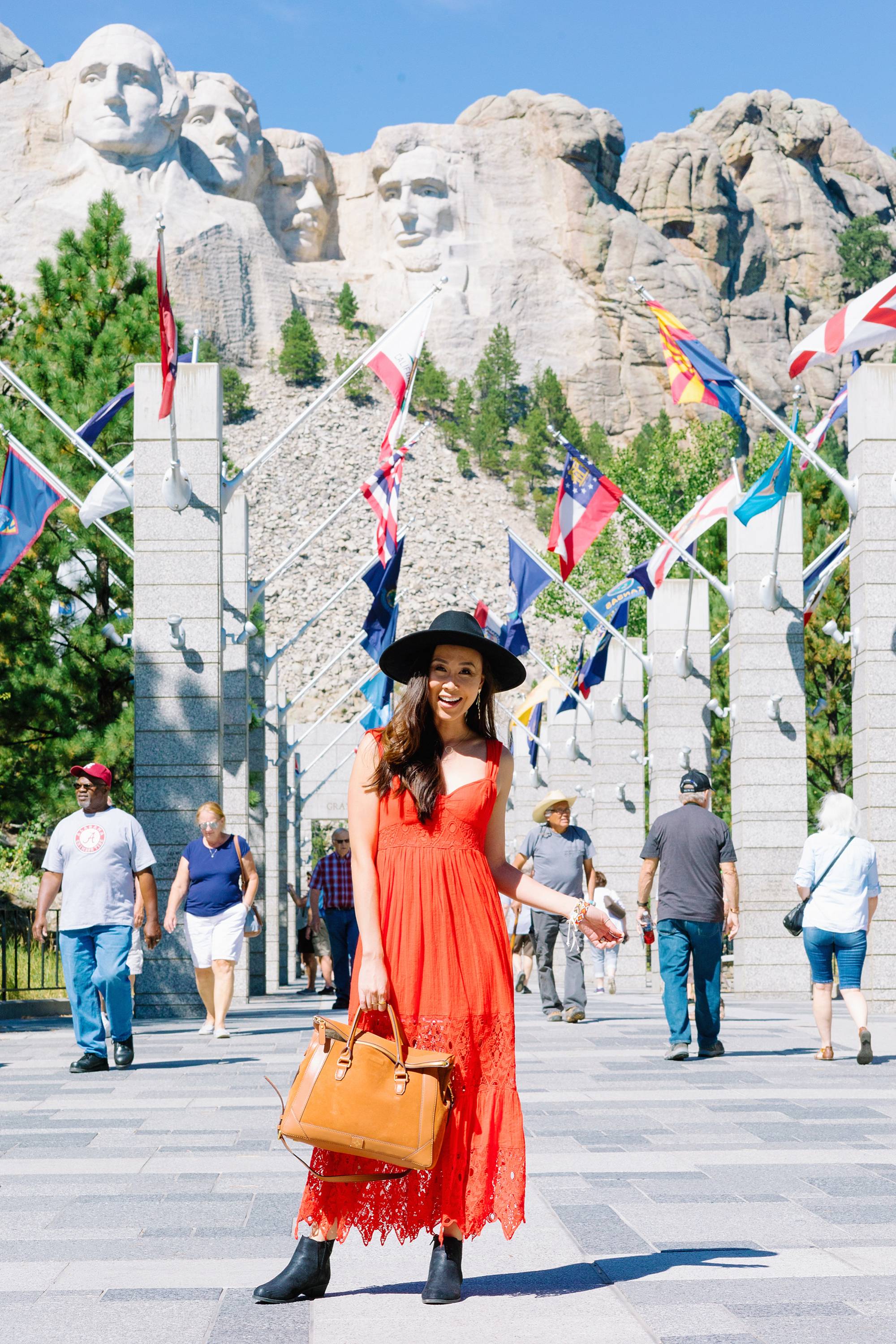 Mount Rushmore in south Dakota posing is Diana Elizabeth lifestyle blogger wearing free people red maxi dress and black wool hat