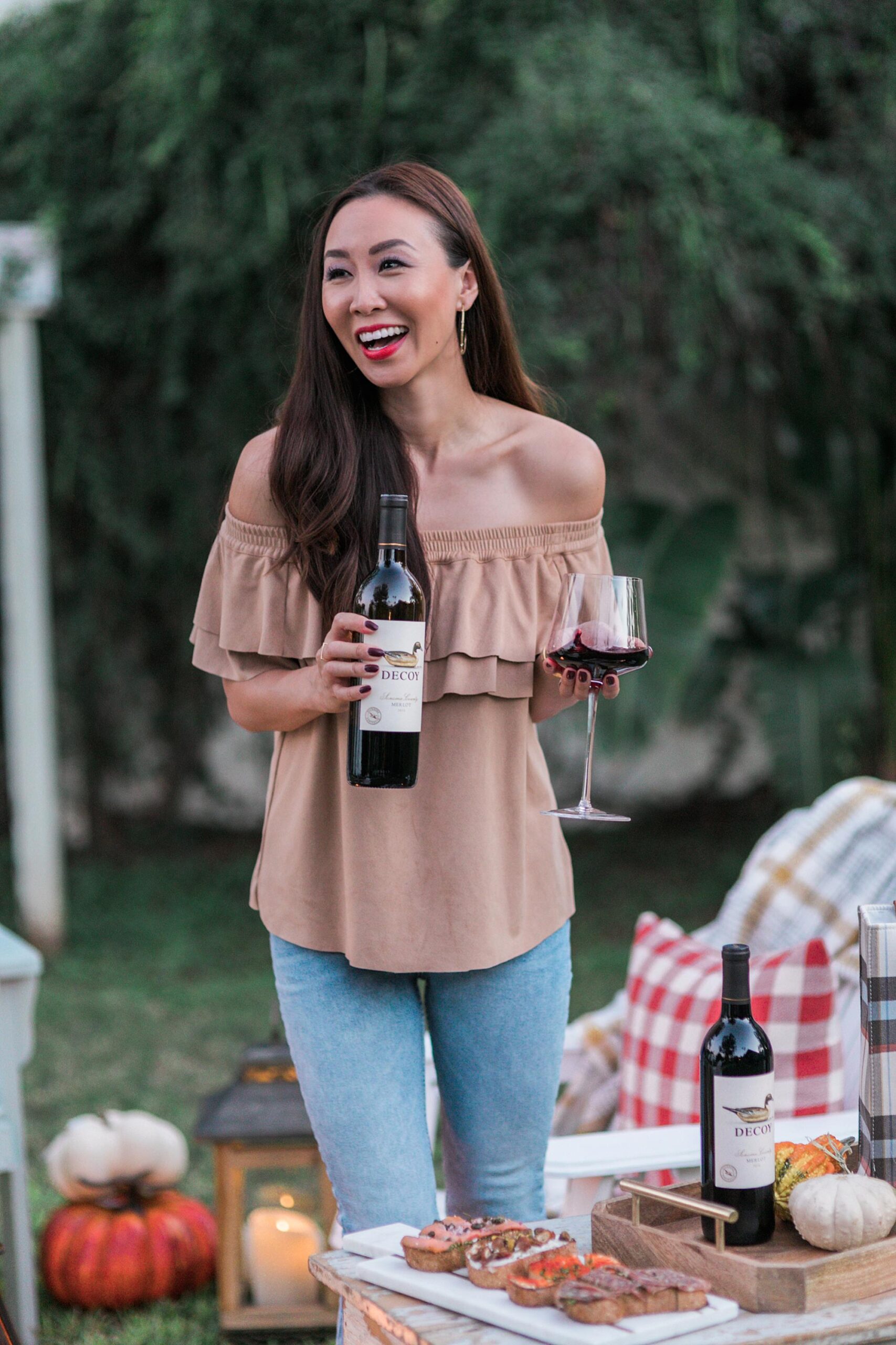 decoy wine merlot to celebrate merlot month of October! backyard setup with fire pit and bruschetta boards with blogger Diana Elizabeth - hay bales pumpkins, gourds and cozy blankets and pillows