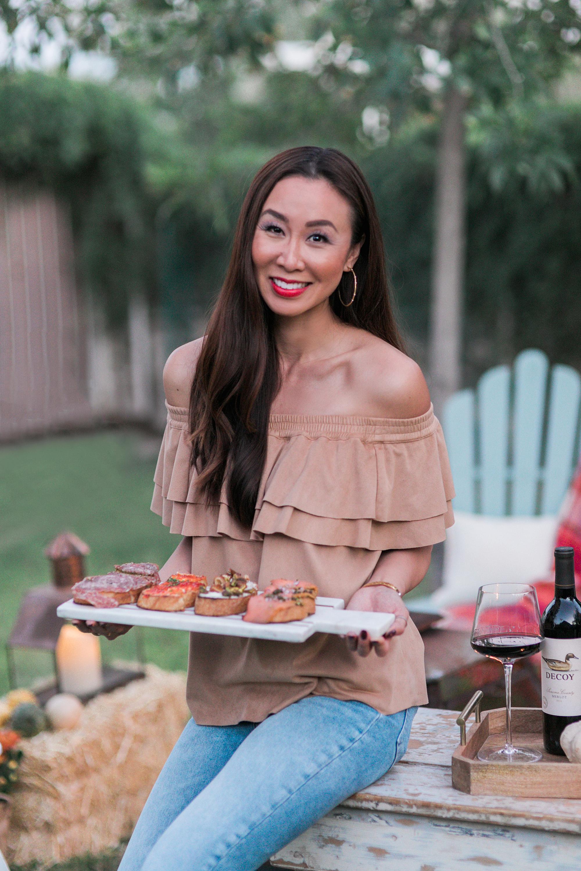 lifestyle entertaining hostess blogger Diana Elizabeth holding bruschetta board to pair with merlot decoy wine for outdoor backyard fall party #fallparty #wineparty