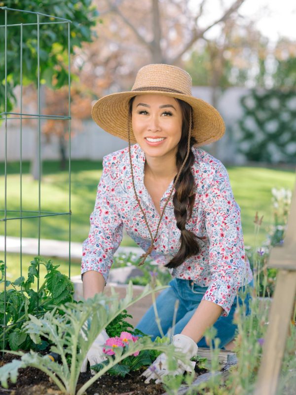 garden lifestyle blogger Diana Elizabeth in backyard garden raised garden beds in phoenix arizona wearing floral print shirt