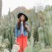 denim jacket orange pants black hat in desert landscape at desert botanical gardens