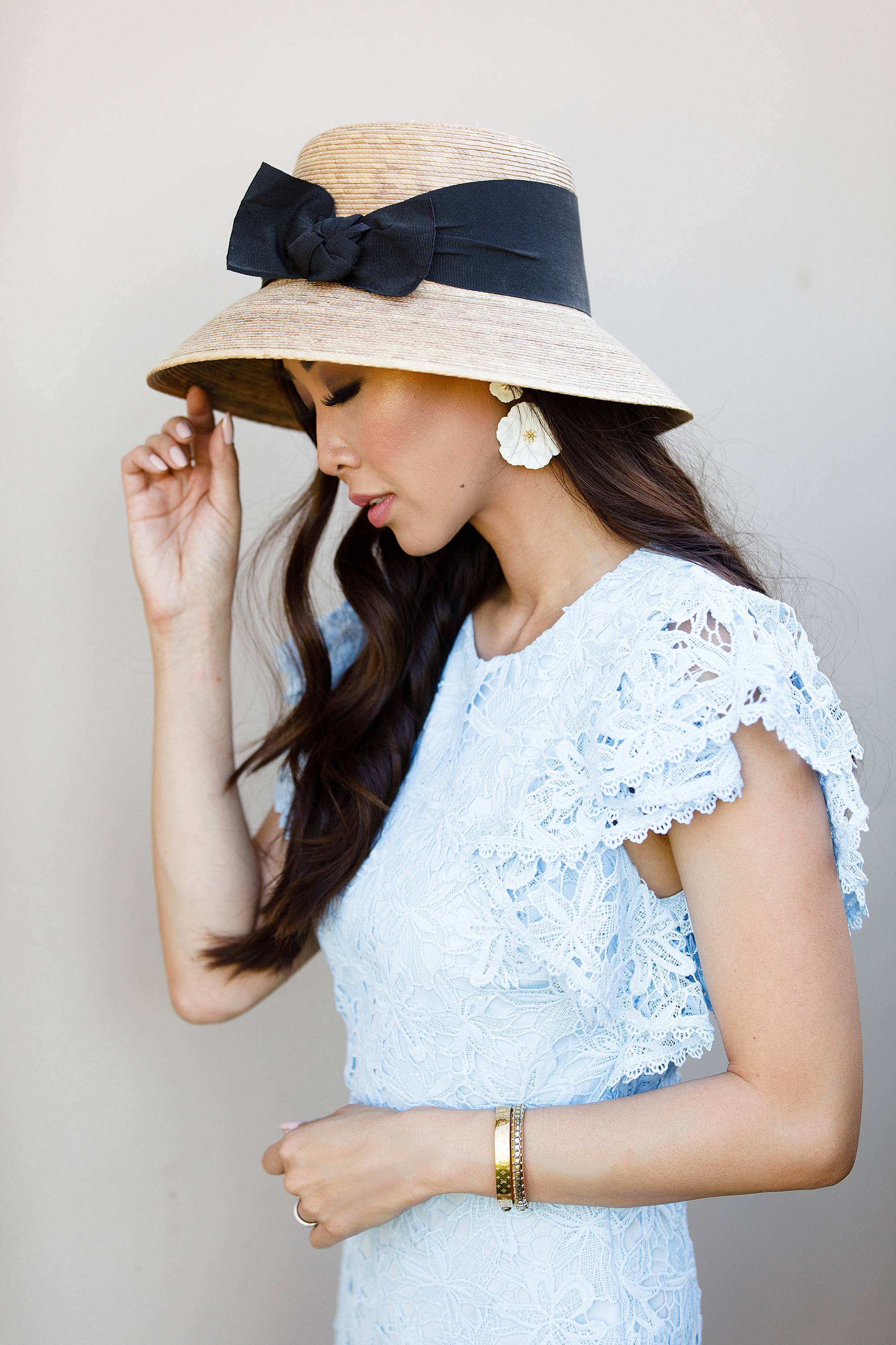 blue lace dress with garden hat from terrain nestled between pink roses against the wall - lifestyle blogger Diana Elizabeth phoenix scottsdale arizona holding rose