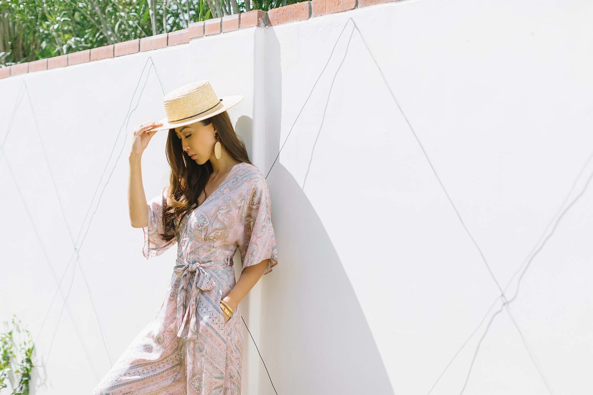 odd Molly radiant jumpsuit phoenix lifestyle blogger Diana Elizabeth leaning up against white wall with hat in shadows