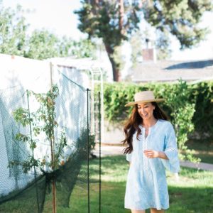 running through home backyard orchard peach tree barefoot in lightweight dress and straw hat
