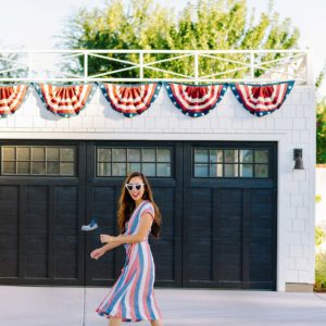 Fourth of July theme garage with American flag bunting on white garage with black garage door