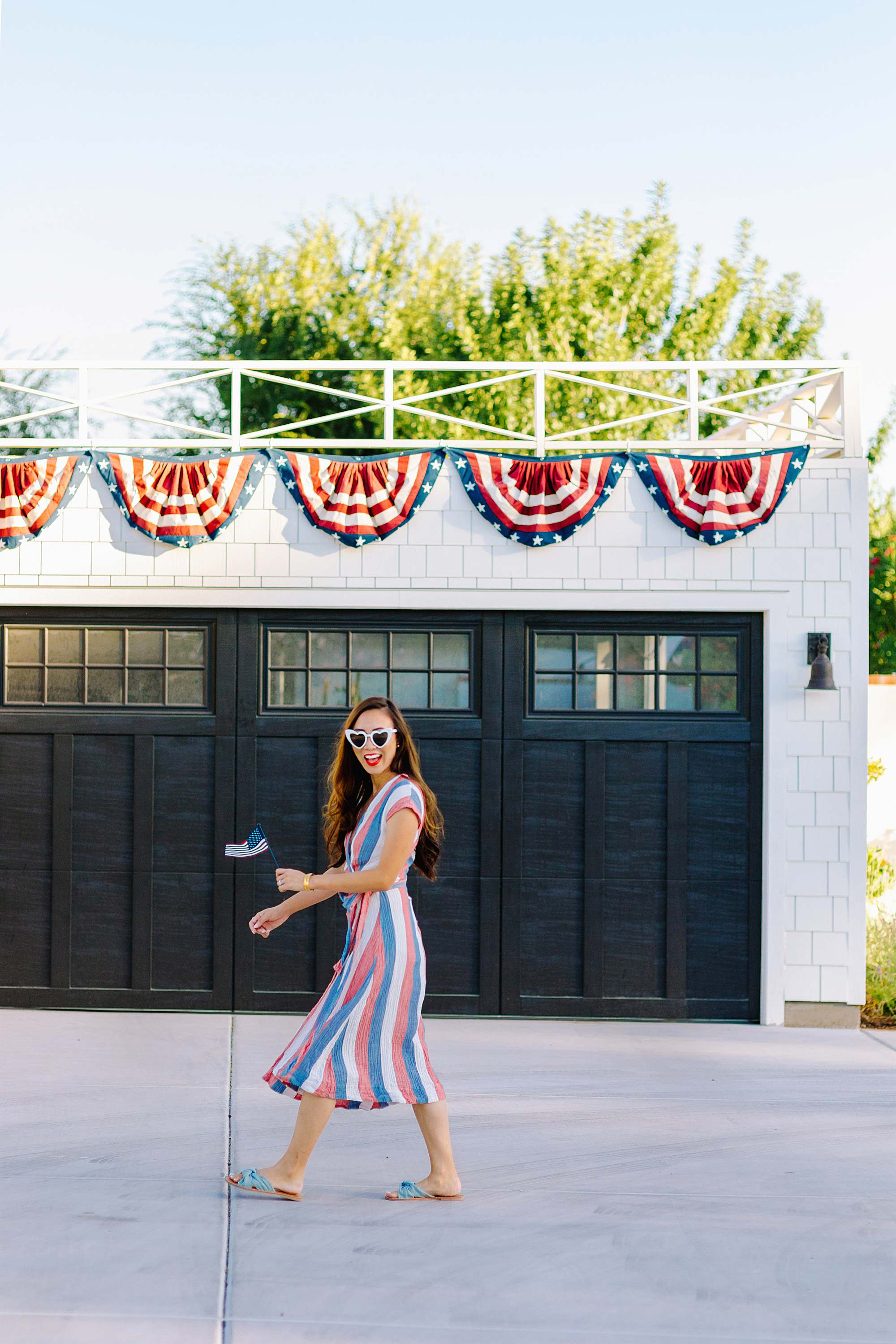 Fourth of July theme garage with American flag bunting on white garage with black garage door