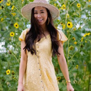 odd Molly Capri dress in yellow standing in front of sunflowers