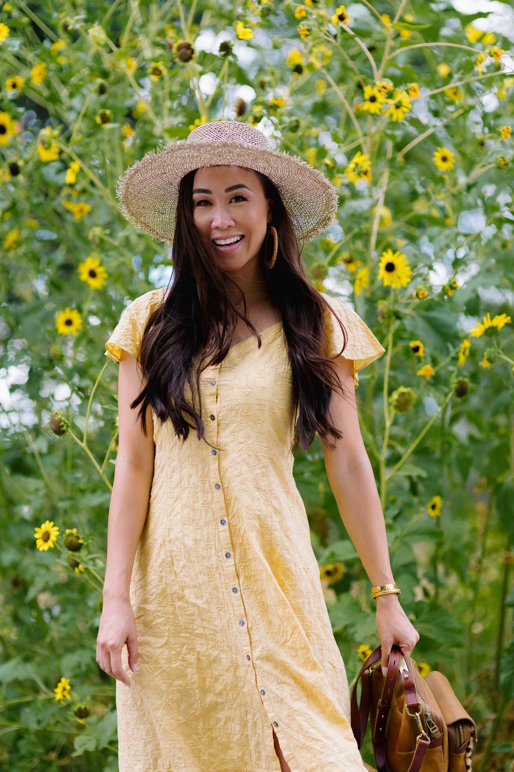 odd Molly Capri dress in yellow standing in front of sunflowers
