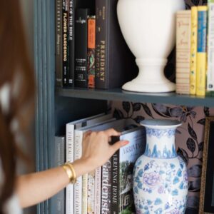 7 favorite interior design books coffee table books // woman holding books by bookcase